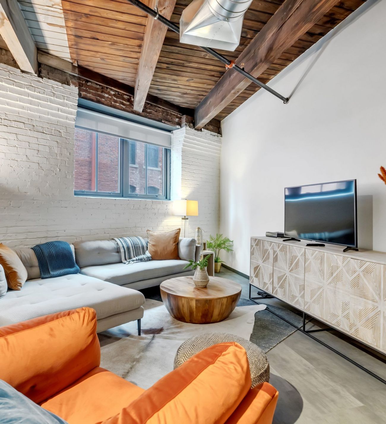 West Bottoms Flats apartment living room with urban core features like raft ceilings, cememt flooring, large windows and modern furniture