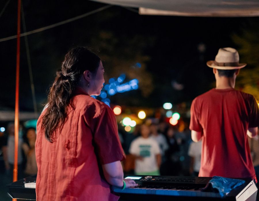 Band playing at an outdoor show featuring a keyboard player looking out at audience