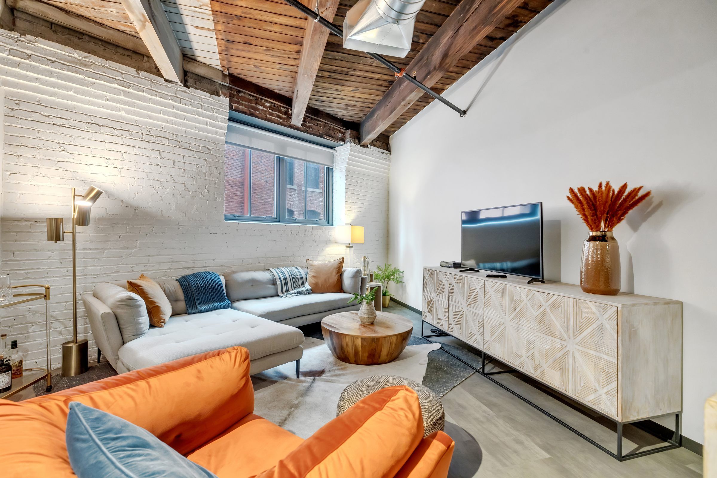 West Bottoms Flats apartment living room with urban core features like raft ceilings, cememt flooring, large windows and modern furniture