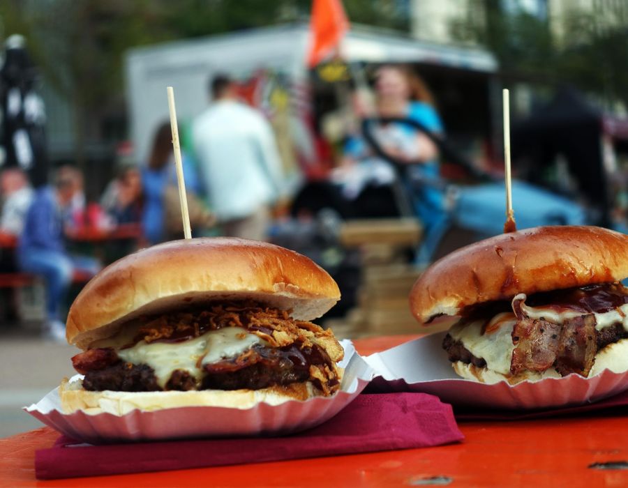 Two pulled pork burgers served at a street event outside with lots of people