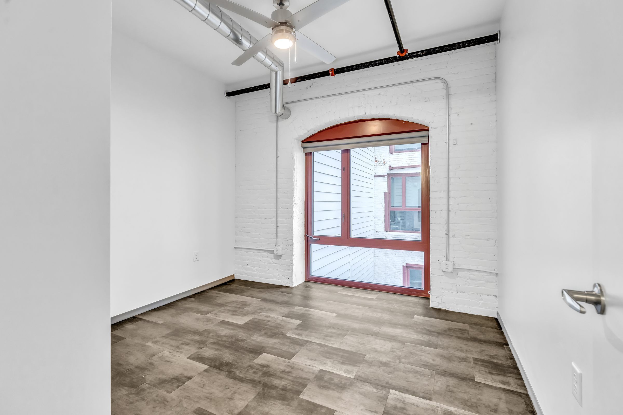 West Bottoms Flats apartment living room with open floor plan and urban core features like high ceilings, large  arched factory windows and modern wood plank tile flooring