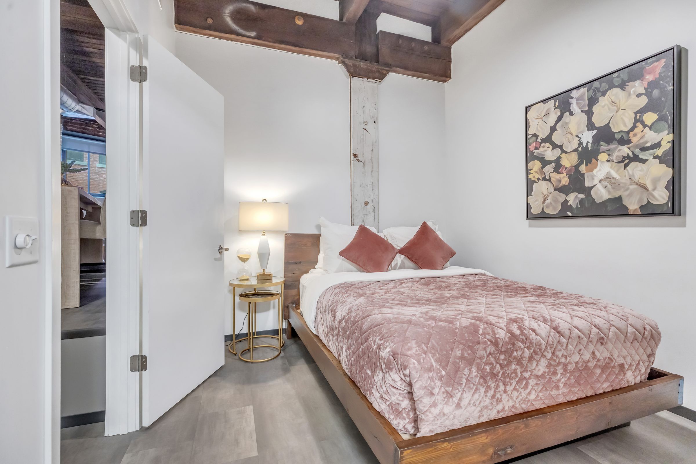 West Bottoms Flats apartments bedroom with high ceilings including wood beams and furnished with a bed and end table