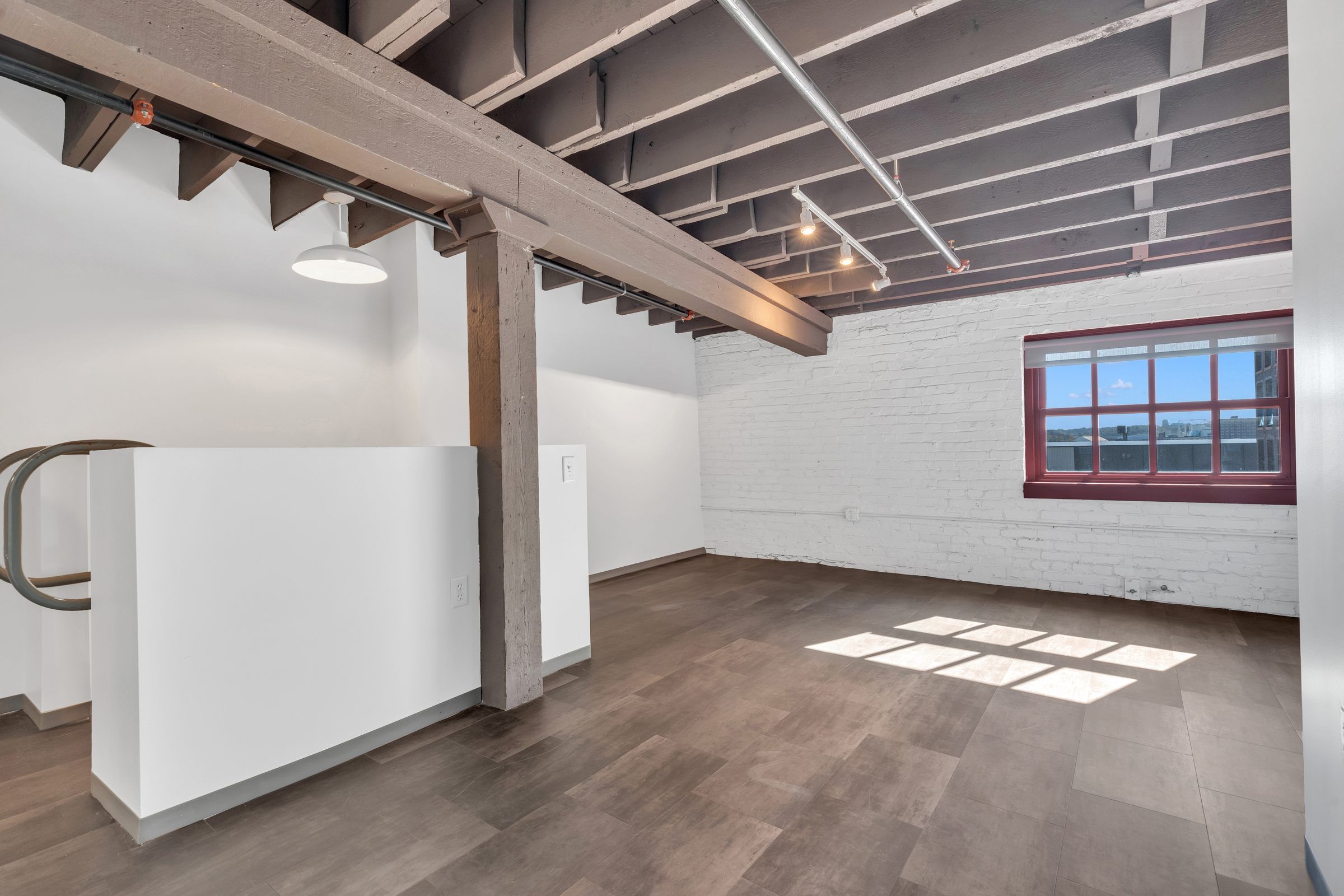 West Bottoms Flats apartments open floor plan including open raft ceilings, wood plank flooring and painted brick walls