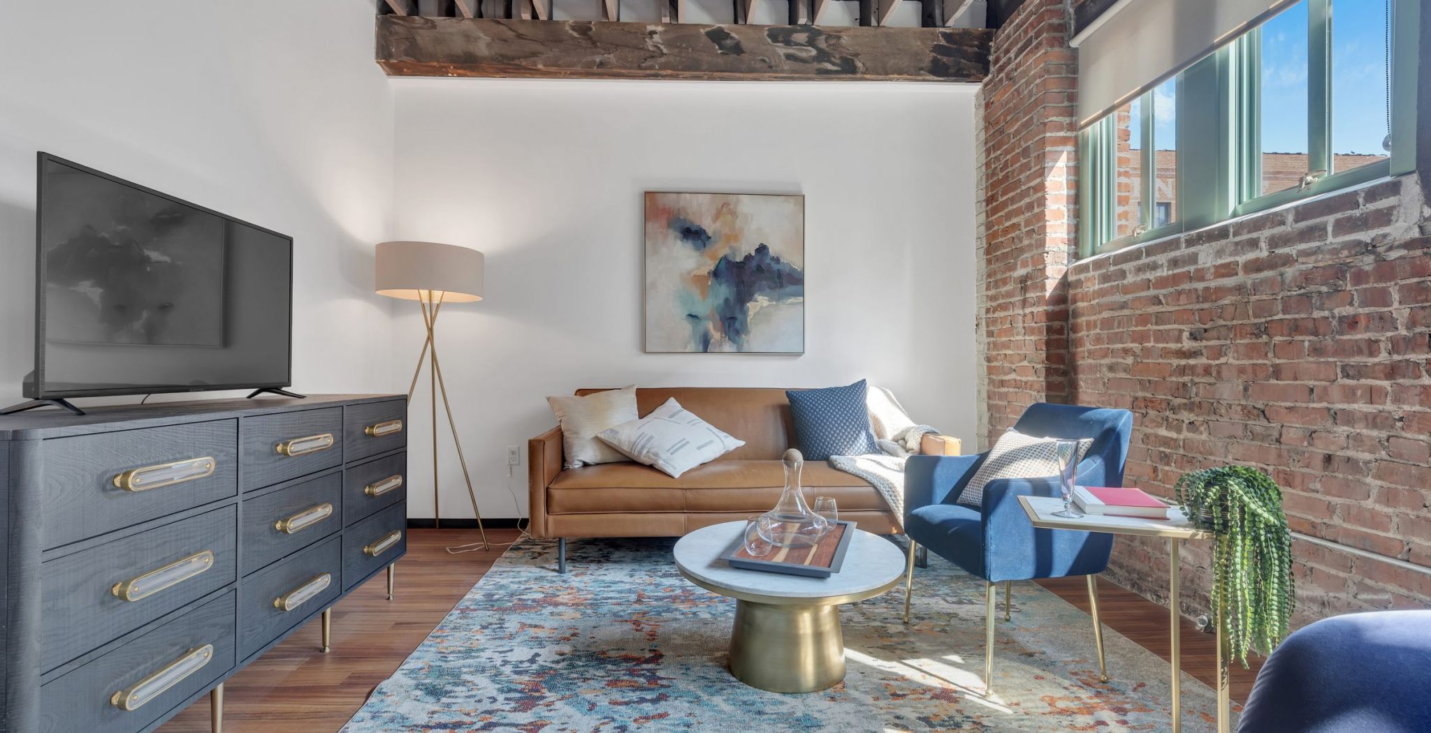 West Bottoms Flats Abernathy apartment living room with exposed brick walls, large windows, and wood floors