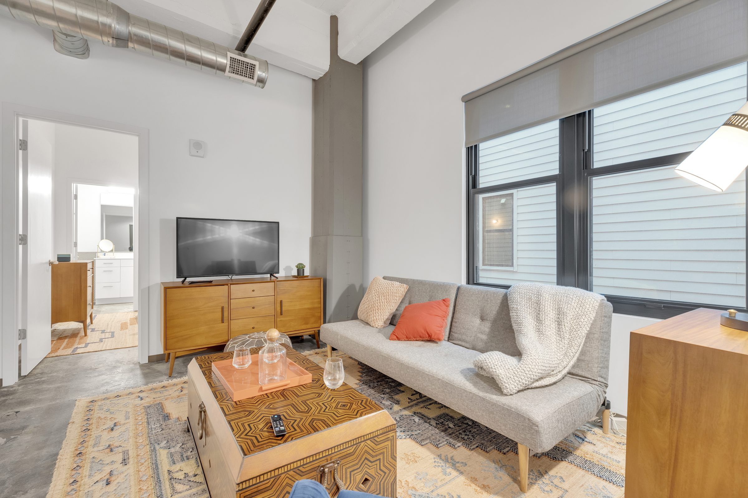 West Bottoms Flats apartment living room with large windows and high ceilings and funished with couch, coffee table and entertainment center