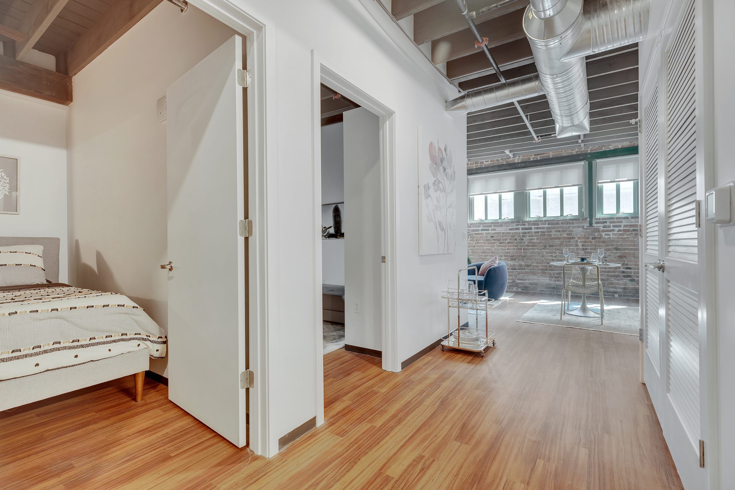 West Bottoms Flats apartments open floor plan including open raft ceilings, wood plank flooring and brick walls with large windows