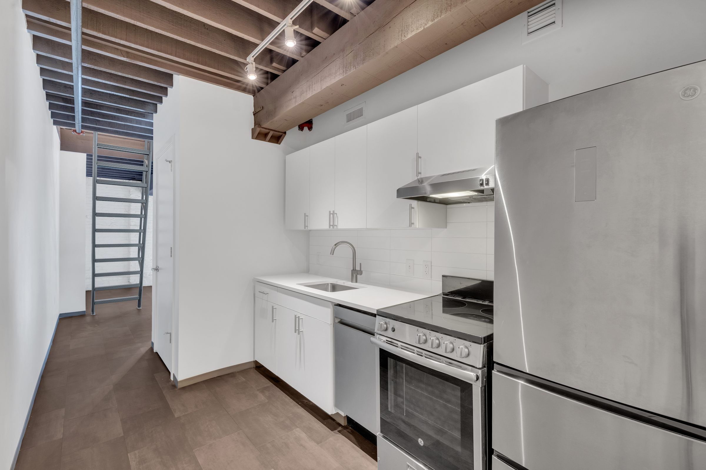 West Bottoms Flats apartment kitchen with open floor plan including white cabinets, stainless steel appliances, an original raft ceilings