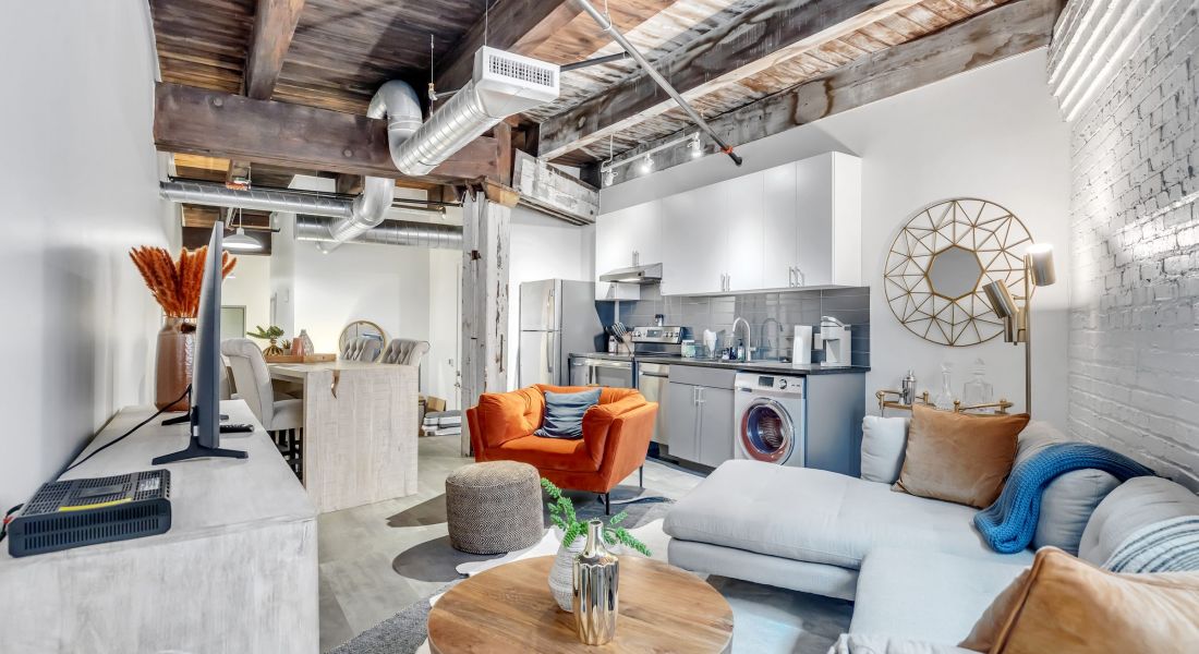 West Bottoms Flats resident lounge featuring high ceilings with exposed beams, white gallery walls, and modern furniture